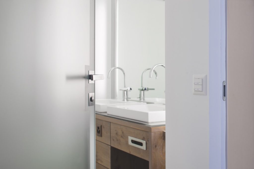 une vue rapprochée sur la porte en verre et aluminium menant à la salle de douche