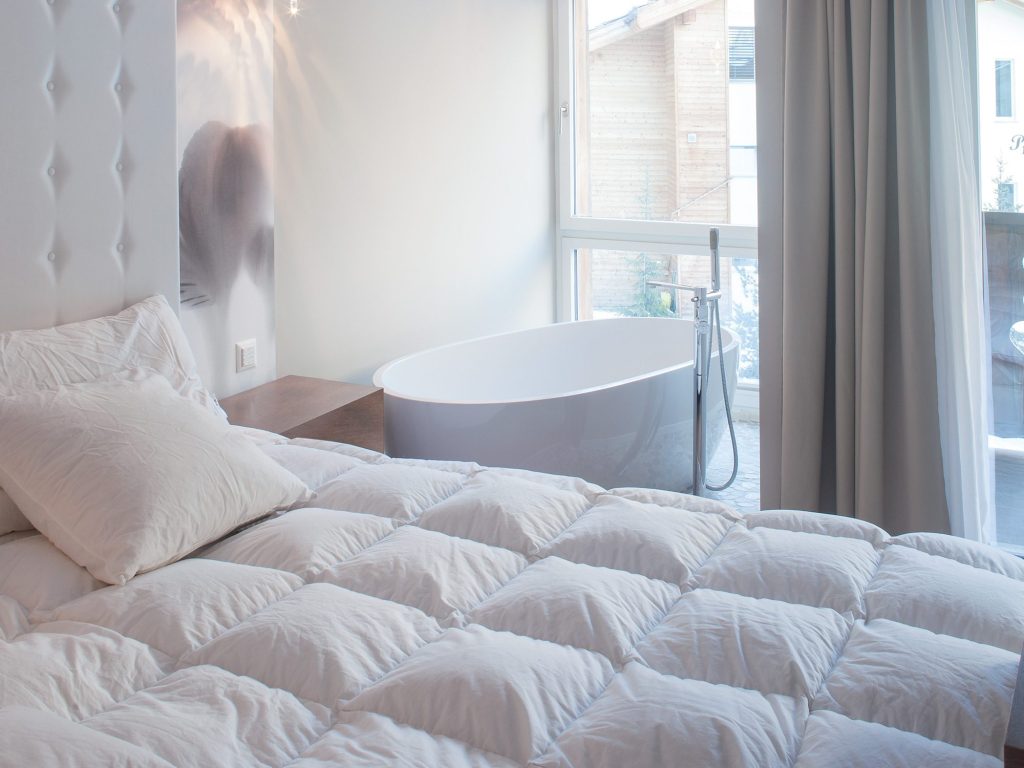 Une chambre à coucher d'un chalet de rêve en suisse avec baignoire attenante au lit donnant sur une baie vitrée