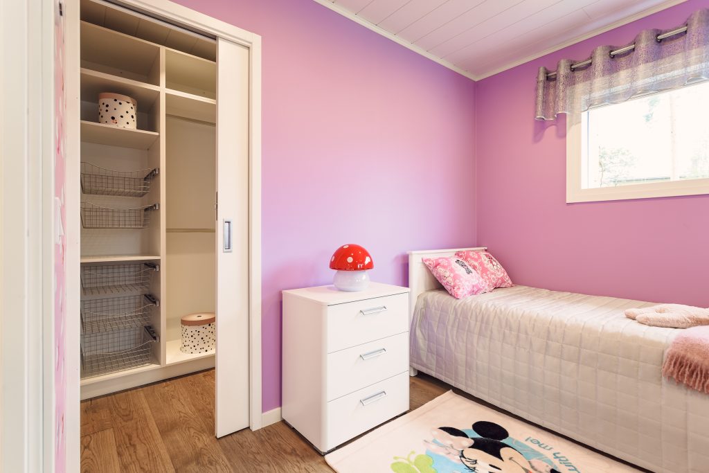 Un espace nuit pour enfant avec un mur rose, une porte coulissante parfaire le tout