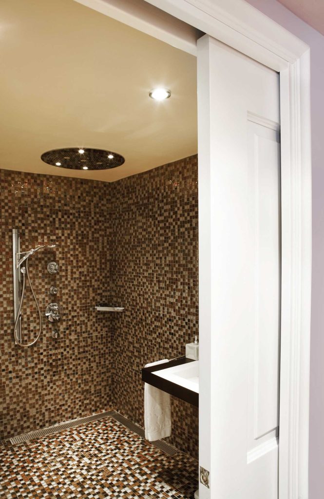 Une porte coulissante menant à la partie salle de douche pour faciliter l'accès PMR