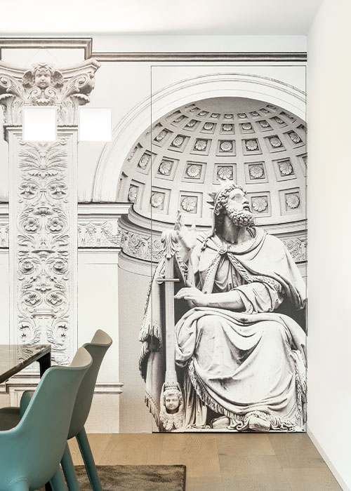 Porte battante affleurante habillée du même papier peint que le reste de la cloison afin qu'elle se fonde parfaitement. Modèle Syntesis Battant par ECLISSE, une huisserie robuste et durable