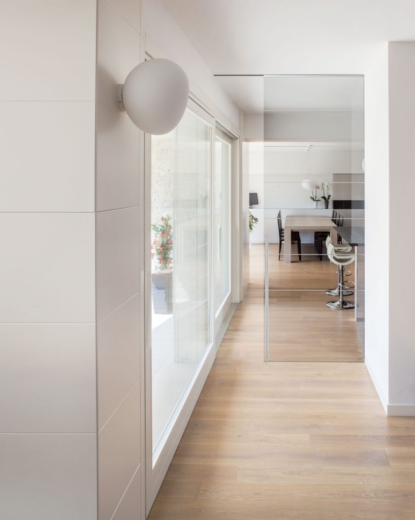 Une porte coulissante en applique au plafond avec une porte tout verre pour laisser entrer la luminosité dans votre espace de vie. Modèle rail en applique par ECLISSE