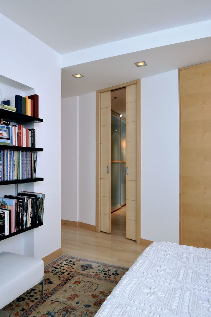 Une porte coulissante double vantaux pour dissimuler parfaitement le dressing de la chambre à coucher. Modèle Unique porte coulissante un vantail avec habillage